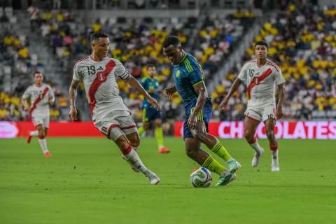 Jugador de la Selección Colombia con uniforme azul conduce el balón ante la marca de jugadores de Perú en el Nu Stadium de Miami