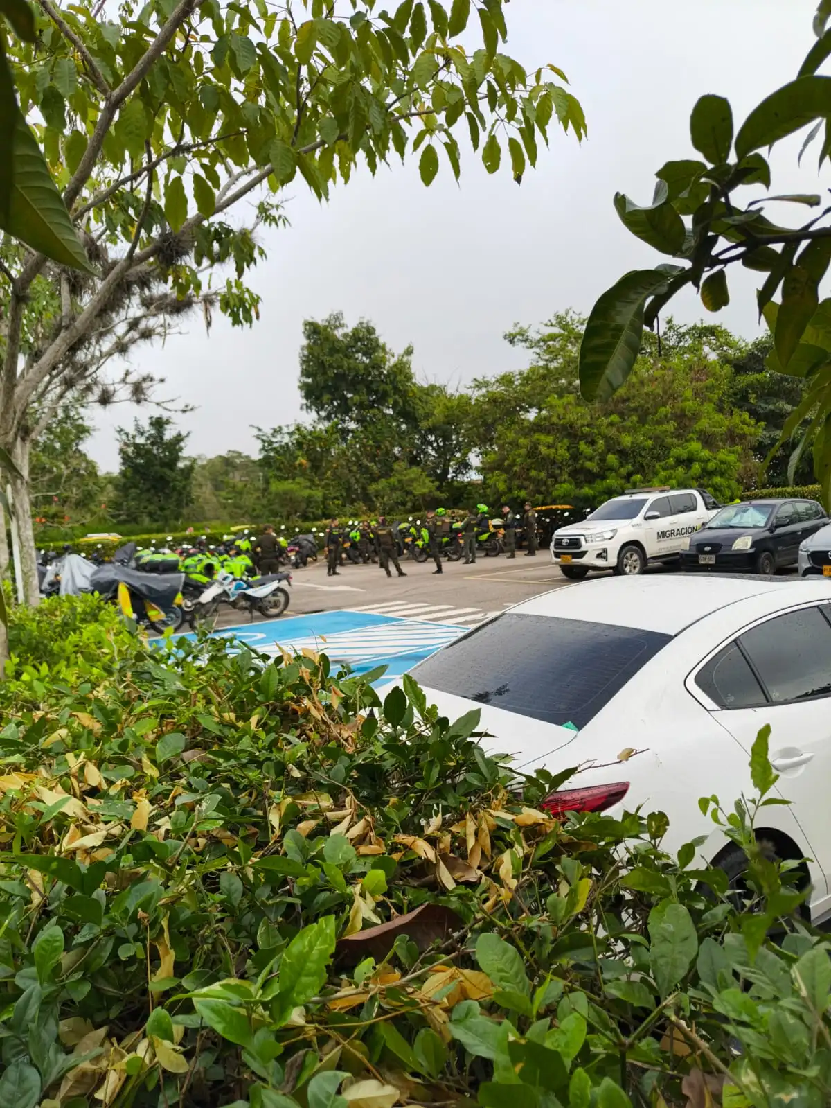 Policías y motocicletas en el parqueadero del aeropuerto Palonegro, junto a una camioneta de Migración Colombia